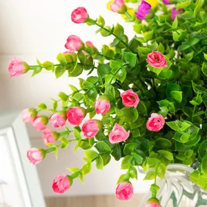 Close-up detail of artificial eucalyptus small rose flower buds, vibrant green leaves and pink.