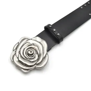Gros plan d'une ceinture en cuir noir punk avec une boucle rose en argent et clous.