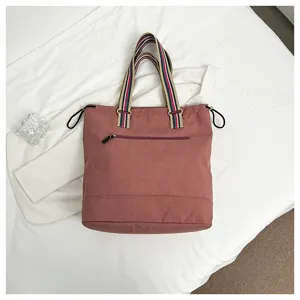 Grand sac cabas en toile terre cuite avec anses rayées et poche zippée à l'avant.