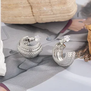 Gros plan sur des boucles d'oreilles créoles texturées en C avec épingles en argent.