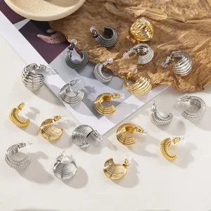 Vue de détail rapprochée de boucles d'oreilles créoles rayées en métal élégant doré et argenté.