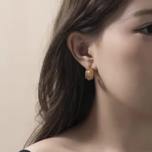 Boucles d'oreilles créoles C dorées et nervurées au design élégant et moderne pour femmes.