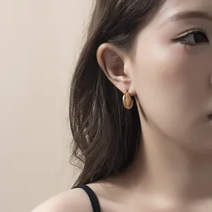 Détail en gros plan de boucles d'oreilles créoles côtelées en métal élégantes portées à l'oreille.