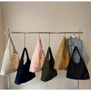 Detail shot of versatile quilted puffer shoulder bags in various colors hanging on a clothing rack.