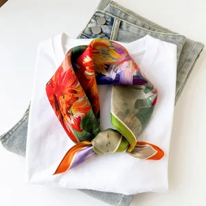 Detail view of the colorful floral print silk square scarf styled on white shirt background.