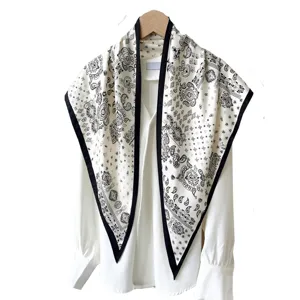 Black and white paisley print triangular scarf neckerchief draped over white blouse.