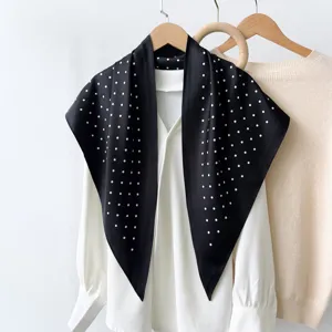 Detailed view of a stylish black polka dot silk triangle scarf hanging with white shirt.