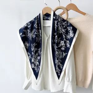 Detailed view of a retro floral silk triangular scarf draped on a chic white blouse.
