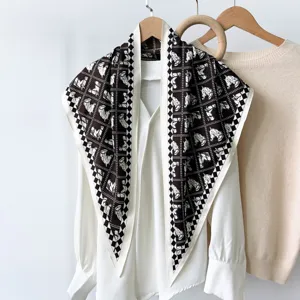 Detailed view of a stylish black and white horse pattern silk scarf draped on a chic blouse.