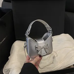 Metallic silver mini handbag detail, featuring a stylish bow and metal chain strap.