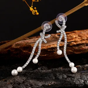Lange strik parel oorbellen met fonkelende zirkonia's, elegante detailopname.