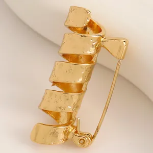 Close-up of creative gold spiral brooch with unique hammered texture design