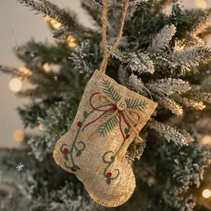 Rustic burlap Christmas stocking ornament with festive pine embroidery on a snowy tree