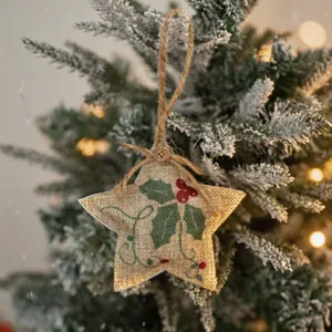 Rustic burlap star Christmas tree ornament with holly embroidery and hanging jute rope.