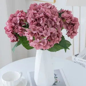 Kunstmatige roze hortensia bloemenboeket in witte keramische vaas voor thuisdecoratie.