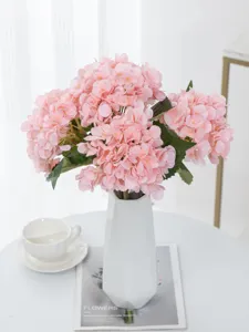 Detailweergave van een kunstmatige hortensiaboeket, roze bloemen in een mooie witte vaas.