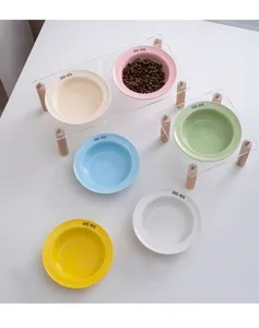 Details van kleurrijke keramische huisdierschalen met helder acryl en houten standaard.