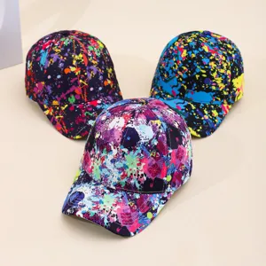 Close-up detail of colorful graffiti paint splatter baseball caps with curved brim.