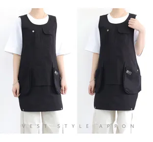 Tablier style gilet noir avec plusieurs poches et boutons-pression, idéal pour cuisine ou café.
