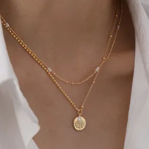 Collier doré superposé avec perles d'eau douce délicates et pendentif coquillage.