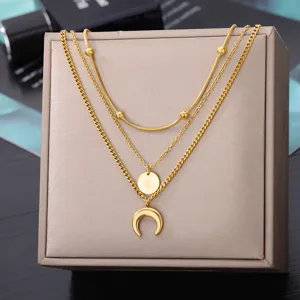 Detail view of a multi-layer gold-colored necklace with moon and star pendants for women.
