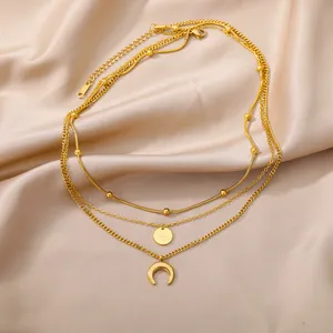 Gold multi-layer necklace detail, featuring a star disc and crescent moon pendant.