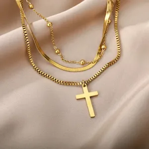 Detailed close-up of multi-layer gold layered necklaces featuring a delicate cross pendant.