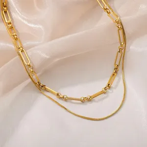 Close up of a stylish double layer gold tone necklace featuring link and snake chain.