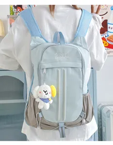 Detail view of cute college style backpack with mesh pockets and plush toy pendant.