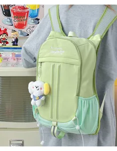 Detailed view of light green student backpack worn on back with cute plush puppy keychain.