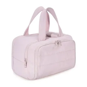 Large capacity quilted travel cosmetic bag with double zipper and portable top handles for use.