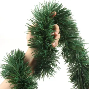 Green Christmas tinsel garland detail showing dense needle texture for holiday decor.
