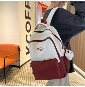 Detailed view of stylish two-tone school backpack with front pocket and cute plush charm.