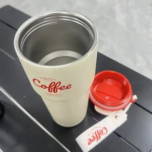 Stainless steel coffee cup with portable strap and red lid for daily outdoor travel use.