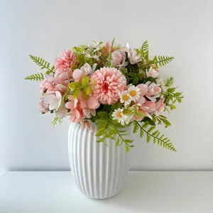 Primo piano di un grazioso mazzo di fiori artificiali rosa in un elegante vaso bianco.
