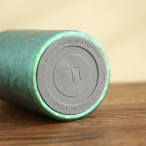 Primo piano dettagliato del fondo della tazza termica portatile in titanio con incisione.
