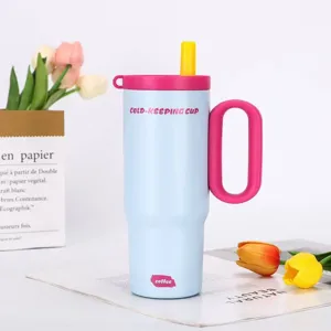 Close-up detail of light blue insulated tumbler cup with pink handle, straw, and floral props.