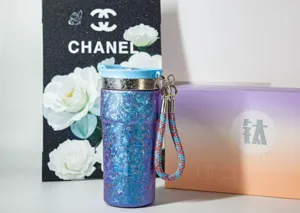 Vue détaillée d'un gobelet isotherme portable en titane avec sangle à paillettes bleues.