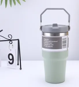 Vue de detail d'un gobelet isotherme en acier inoxydable avec poignee grise et corps vert design.