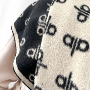 Nahaufnahme eines dicken Kaschmirimitat-Schals mit doppelseitigem schwarzen und beigen Jacquard.