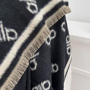 Detailaufnahme der weichen Fransen und des Jacquard-Buchstabenmusters des Schals