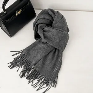 Close-up of premium gray wool scarf with fringe and classic labels next to handbag