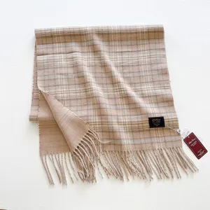 Vista detallada de una bufanda de lana a cuadros beige retro con flecos y marca tejida.