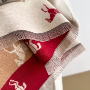 Detailopname van een zachte imitatie kasjmier sjaal met rode paardenpatronen en franjes.