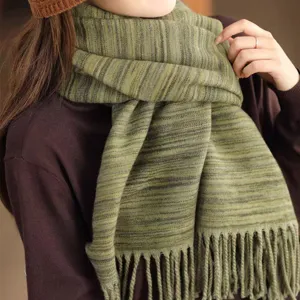 Nahaufnahme eines weichen grün gestreiften Strickschals mit eleganten langen Fransen