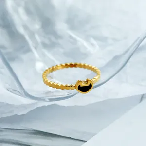 Gros plan sur une bague à motif ondulé dorée avec un médaillon Ruyi noir central