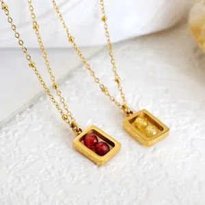 Detailopname van gouden geometrische hangers met rode en gele gefacetteerde kralen