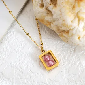 Detailopname gouden geometrische ketting met twee roze gefacetteerde zirkonia's