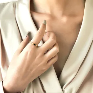 Gros plan d'une bague dorée ondulée ornée d'un mini pendentif cadenas Ruyi noir