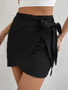 Detalle de la minifalda cruzada de talle alto lisa con lazo lateral estilo de verano.
